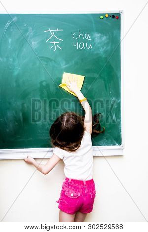 Girl Wipes A Green School Board From Chinese Characters