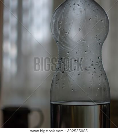 Two Liter Bottle Of Water With Drops And Standing Next To A Mug Close-up