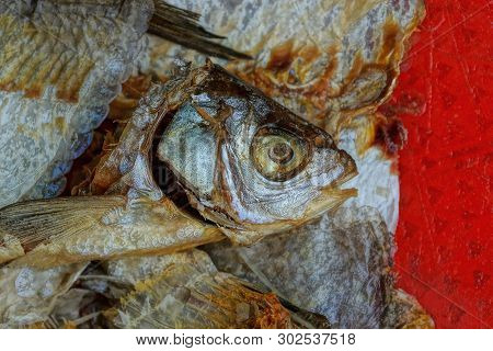 Trash From A Pile Of Pieces Of Fish From Bones And Heads On A Red Table
