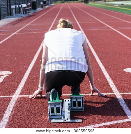 The View From Behind The Starting Blocks Of A High School Female Sprinter Ready To Run Down The Trac