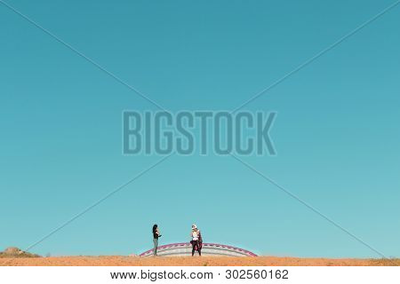 Female Pilot Landing With A Paraglider In The Field With A Blue Sky Background