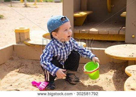 The Boy Plays In The Sand In The Sandbox. Childrens Games. Sandbox. Childrens Sand Tins. Happy Boy .