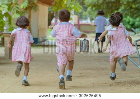 Back View Of Kindergarten Students Run Back To The Classroom After Having Lunch.