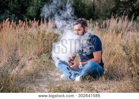 Modern Man Enjoying An E-cigarette. Man Really Likes Process Of Smoking.