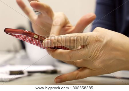 Smartphone In Female Hands Close Up, Woman Using Mobile Phone In A Office. Соncept Of Online Addicti