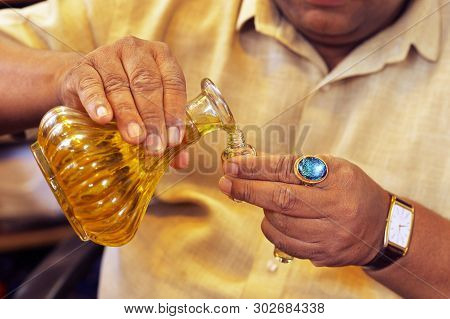 Man Pouring Essential Oil From Glass Bottle Close Up