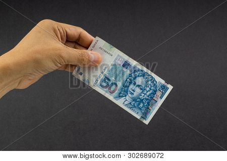 Hand Holding Fifty Croatian Kuna Or Sto Kuna Bank Notes On Black Background. Financial Concept And S