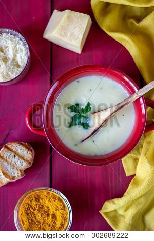 Cheese Cream Soup On A Red Wooden Background. White Bread Croutons. Ingredients.