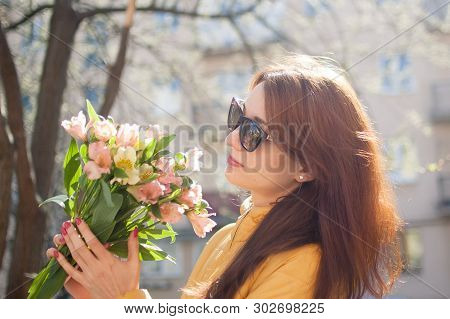 Sensual Young Girl In Dark Sunglasses Has Just Received A Big Bouquet Of Colorful Flowers Outdoors N