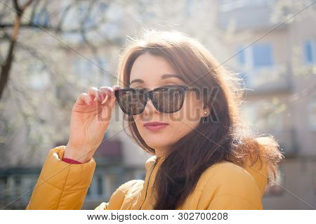 Pretty Female Model With Sensual Lips In Yellow Jacket Wearing Dark Fashionable Sunglasses.