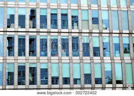 New Office Building In Business Center. Wall Made Of Steel And Glass With Blue Sky.