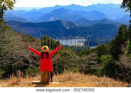 Woman looking over the mountain landscape with the Oyunohara torii gate, the tallest in the word, Japan