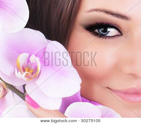La moitié de visage de magnifique jeune mannequin, yeux belle femme avec la fleur d'orchidée rose fraîche, partie de femal