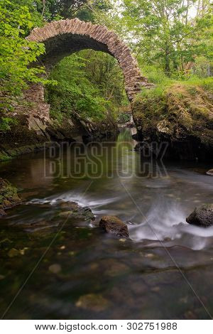 A View Of The Ancient Cromwell Bridge In Kenmare, County Kerry, Ireland, Taken From Upstream On A Lo