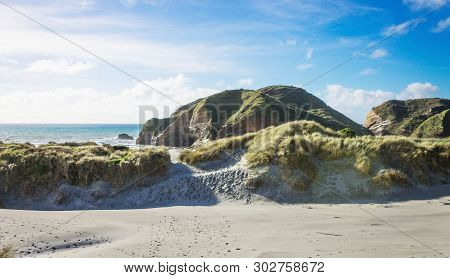 Footprints Through The Sand Dunes Leading Down To Wharariki Beach. Wharariki Beach Is West Of Cape F