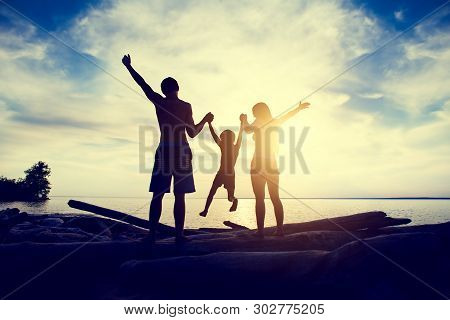 Toned Photo Of Happy Family Silhouette With Hands Up On The Sunset Background