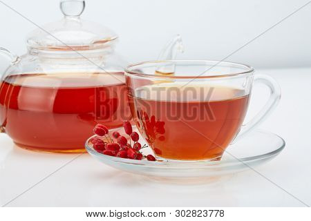 Healthy tea with barberries in glass cup on on a white background.