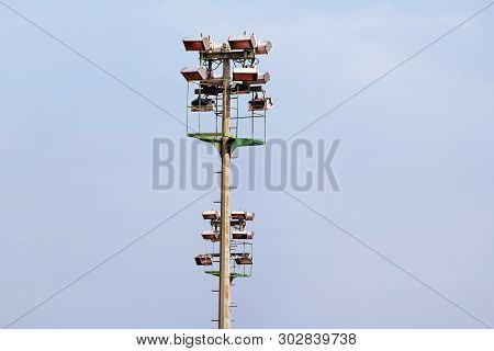 Stadium Floodlight Tower With Reflectors With Blue Sky. Lighting Pole Tower At The Sports Stadium An