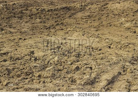 Clay Is Not Fertile Soil, Background Texture. Earth Dirt Clay Soil, A Mound Of Earth With Boots