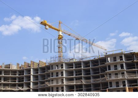 Yellow Construction Crane Working On The Construction Of A Multi-storey Residential Building. New Re