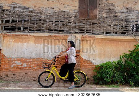 Loei, Thailand - February 26, 2018: An Elderly Asian Woman On A Bicycle Ofo Is A Bicycle Sharing Ser