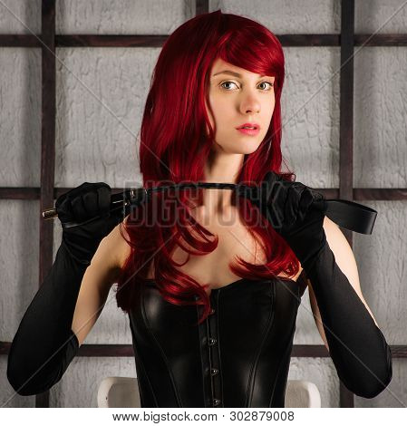 Red-haired Girl In A Leather Corset Holds Spank. Bdsm Outfit