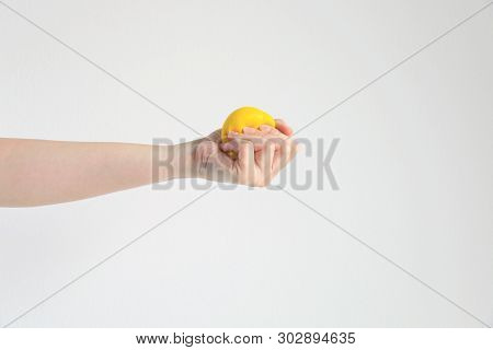 A Hand Hold And Pressing Yellow Squishy Ball (squeezing Ball Toy) For Exercise Muscle Or For Relieve