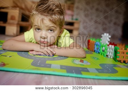 Adorable Gingerish Little Boy Laying On Floor, Playing With Building Cubes.