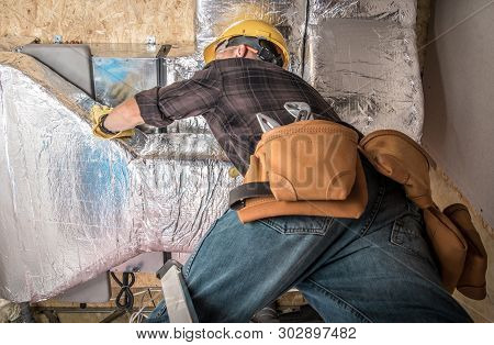 Worker In Yellow Hard Hat Installing Furnace And Central Heating Pump Duct. Heating And Cooling Work