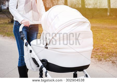 Woman In White In White Jacket, Blue Jeans And Grey Scarf Strolling With White Baby-carriage. Flare.