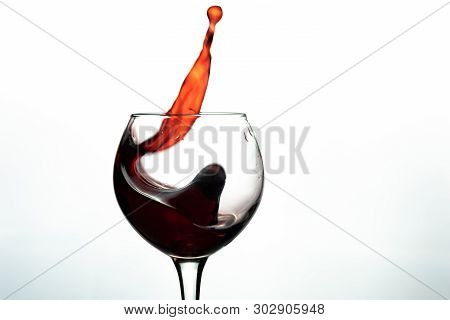 Red Wine Splash Into Glass On White Background.