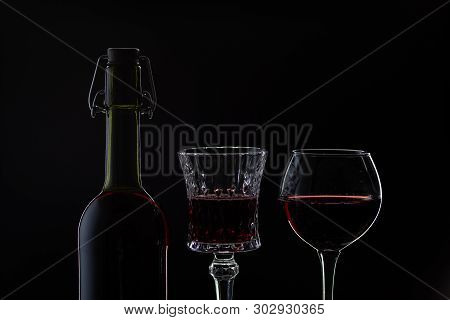 Wine. Red Wine In Two Wine Glasses Over Dark Background. Silhouette Of Bottle With Rose Wine And Ope