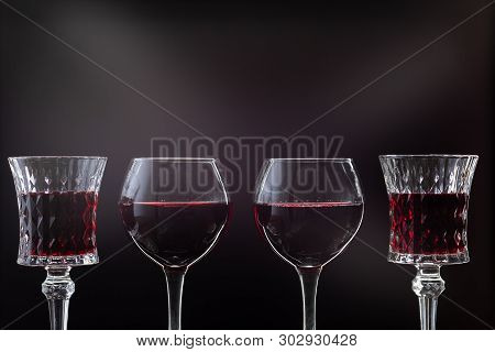 Rose Wine. Red Wine In Four Wine Glasses Over Dark Background With Rays Of Light.