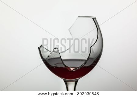 Broken Wine Glass With Red Wine On White Background.