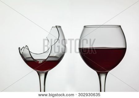 Broken And Not Broken Wine Glass With Red Wine On White Background.