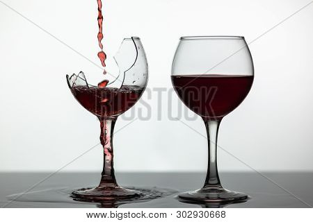 Wine. Red Wine Pouring Into Broken Wine Glass On The Wet Surface. Rose Wine Pour. Close Up Shot. Whi