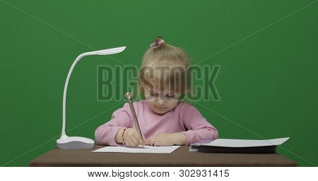 Girl Drawing At The Table. Education Process. Happy Three Years Old Child. Cute Girl Smiling. Brown 