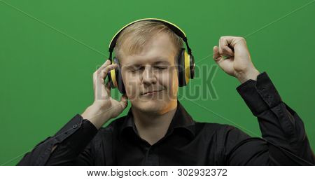 Guy Listens To Energetic Music In Wireless Yellow Headphones And Dances. Portrait Of Attractive Man 