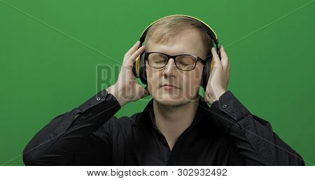 Guy Listens To Energetic Music In Wireless Yellow Headphones And Dances. Portrait Of Attractive Man 