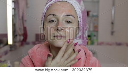 Woman Applying Mask Moisturizing Skin Cream On Face And Looking At Camera In Bathroom. Girl Taking C