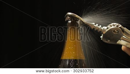 Opening Cold Bottle Of Beer With Bottle Opener. Cold Beer On A Black Background. Craft Light Beer In