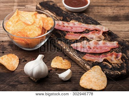 Potato Crisps With Backon Flavour With Grilled Bacon Rashers On Vintage Chopping Board With Garlic A