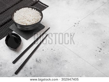Black Bowl With Boiled Organic Basmati Jasmine Rice With Black Chopsticks And Sweet Soy Sauce On Bam
