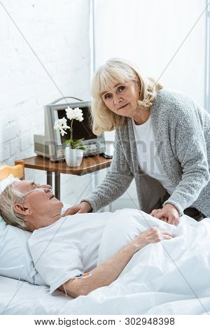 Sad Senior Woman With Husband In Coma In Hospital