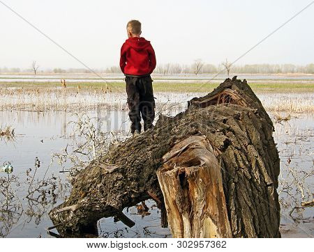 In The Spring Flood On The Volga, A Boy In A Red Sweater Admires The Spill Of A River, Climbing A Po