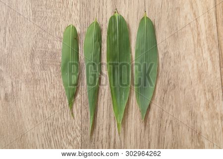 Four Green And Fresh Bambou Leaf On Wood Table