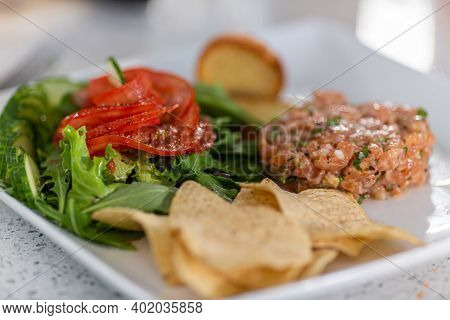 Close Up Shot Of Single Serving Of Tartare De Saumon Avec Fleur De Tomate, Background Has Been Blurr