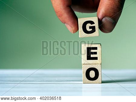 The Hand Puts The Cube Block With The Inscription Geo