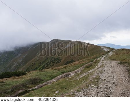 Footpath Of Hiking Trail From Chopok At Mountain Meadow, Grassy Hill Slopes With Thick Fog And Cloud