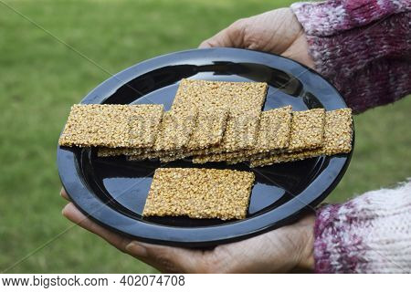 Female Hand Holding Winter Special Sweet Dish Of White Sesame And Jaggery Melted In Clarified Butter